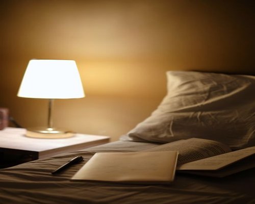 A nightstand with a warm lamp illuminating an open book