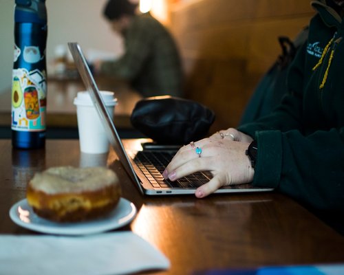 Person taking a break from working on their laptop in a well-lit cafe